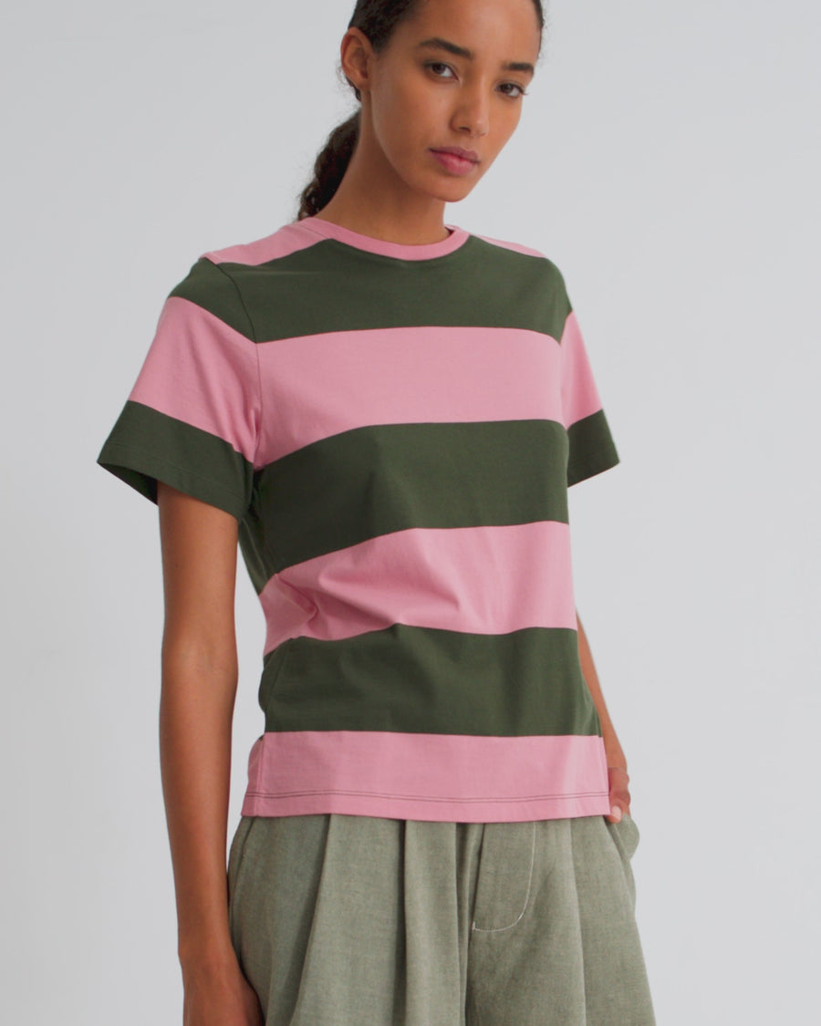 A women wearing a pink and green striped tee and green belted shorts.