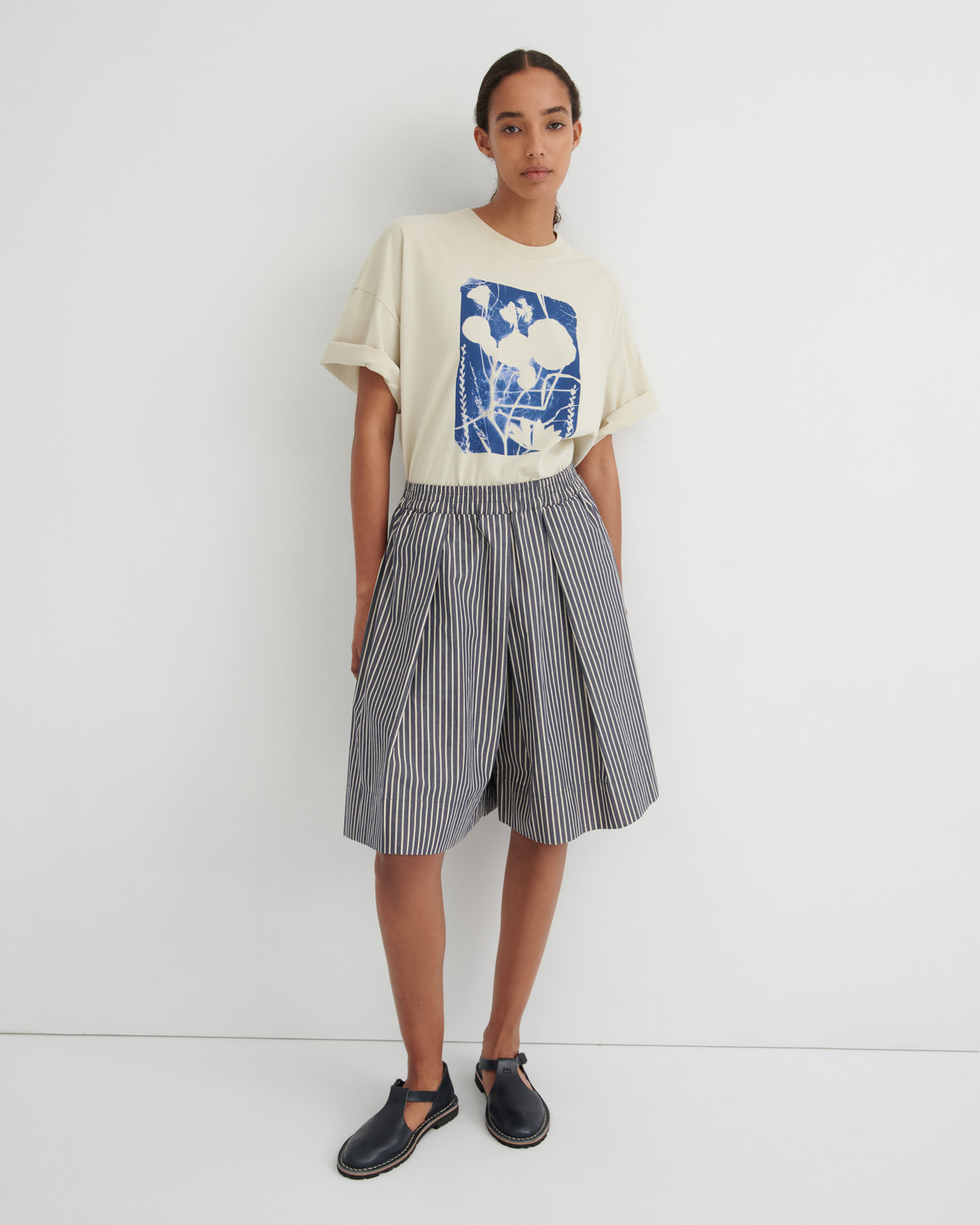 Person wearing a graphic t-shirt and striped skirt on a white background