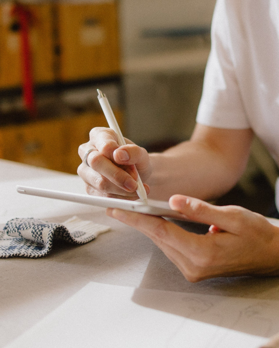 A women holds an ipad and a pen in a design studio.