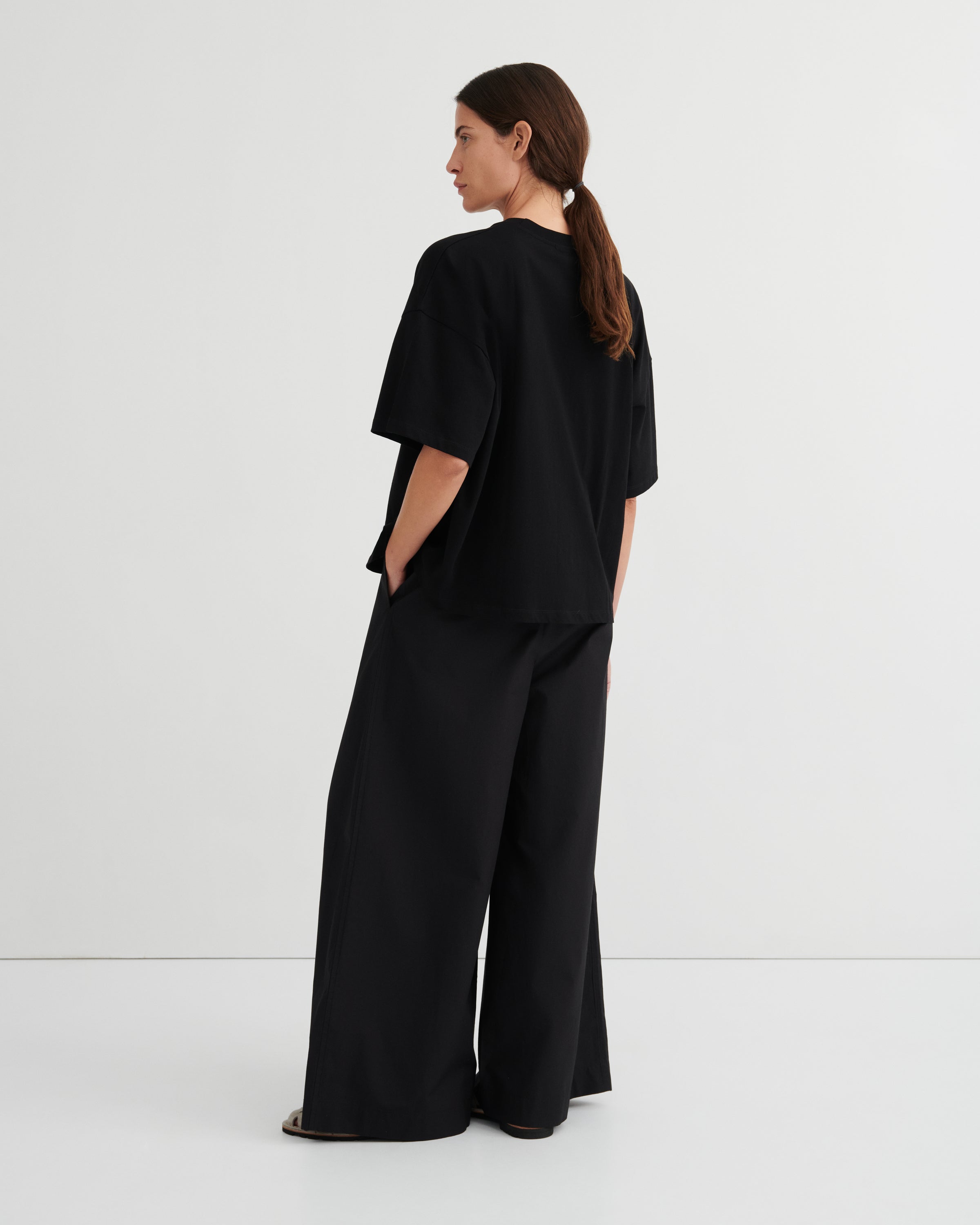 Person wearing a black outfit with wide-leg pants on a white background