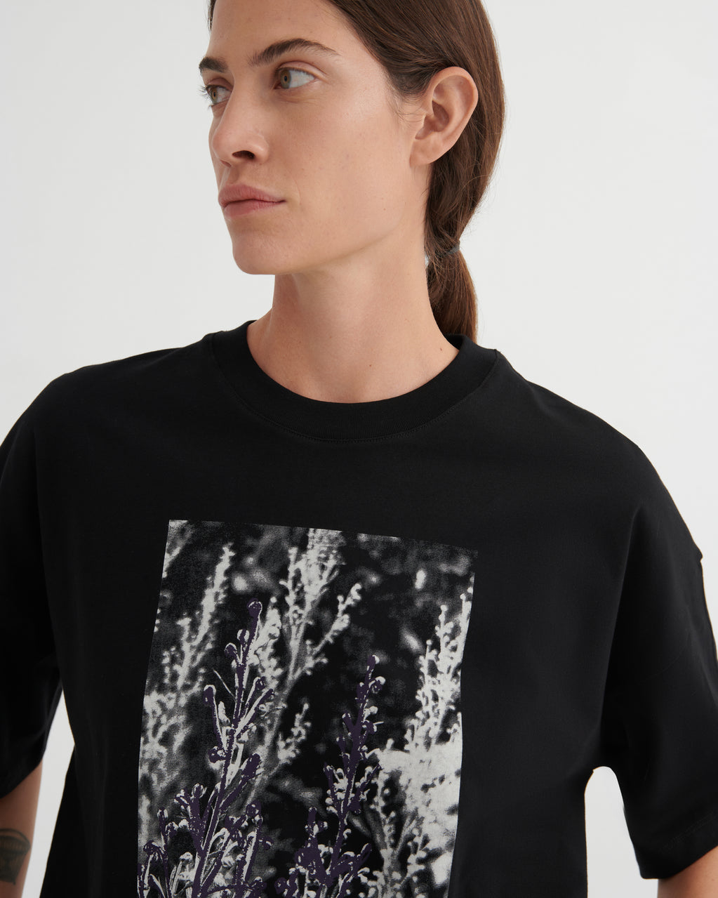 Person wearing a black t-shirt with a graphic design on a plain background