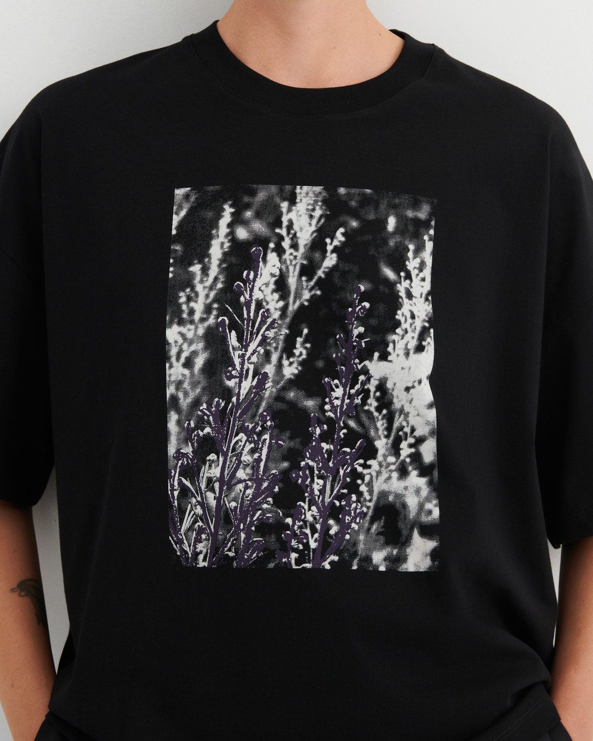 Black t-shirt with a graphic of purple flowers on a plain background