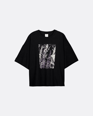 A black short-sleeve t-shirt with a square abstract graphic print in black, white, and gray on the front, displayed against a light gray background.