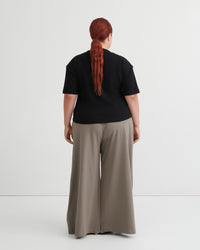Person wearing a black top and beige pants on a white background